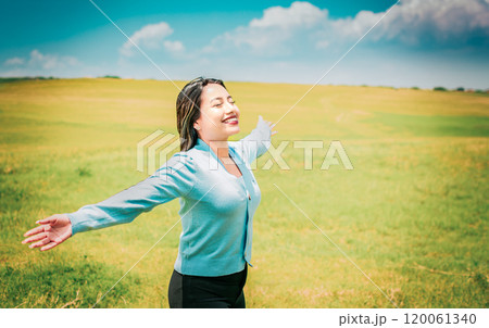 Serene young woman breathing fresh air in beautiful field spreading arms. Happy girl spreading arms breathing fresh air in the field 120061340