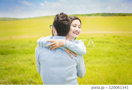Close up of a happy couple hugging in the field, a young couple in love hugging in the green field, A man hugging his woman in a beautiful field 120061341