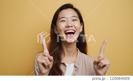 Asian Woman Happily Pointing to Upper Side with Both Fingers in Studio 120064009
