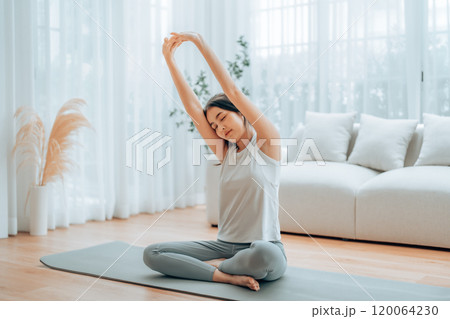 Happy young Asian woman practicing yoga and shoulder stretching at home Happy young Asian woman practicing yoga and shoulder stretching at home 120064230
