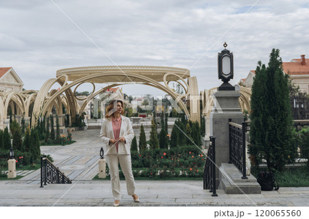 Woman, Hat, Garden - Elegant woman wearing a hat stands in a garden with a unique archway structure. Woman, Hat, Garden - Elegant woman wearing a hat stands in a garden with a unique archway structure. 120065560