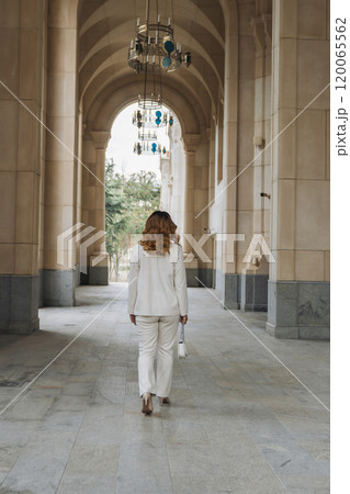 Woman White Suit Walking Arched Corridor Building Entrance Woman White Suit Walking Arched Corridor Building Entrance 120065562