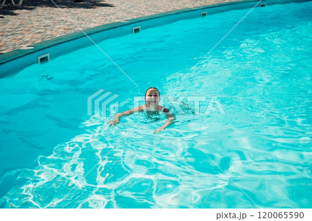 A woman is swimming in a pool. The pool is surrounded by a fence and has a playground in the background. A woman is swimming in a pool. The pool is surrounded by a fence and has a playground in the background. 120065590