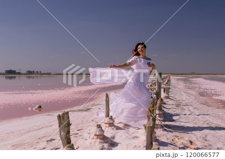 Bride, Pink Lake, Australia - Woman in white dress poses by pink salt lake in Australia for wedding photography. 120066577