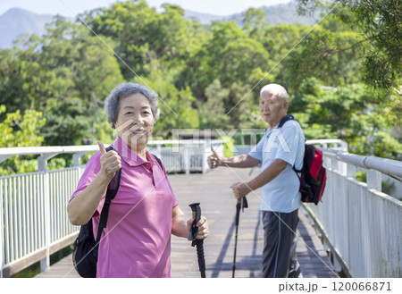 Happy asian senior couple hiking in the nature and showing thumbs up 120066871