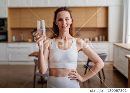 Young woman with a glass of water in the kitchen Young woman with a glass of water in the kitchen 120067801