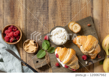 Breakfast concept, dessert french pastry. Tasty freshly baked open croissants with cream cheese and raspberry on a rustic background. Breakfast concept, dessert french pastry. Tasty freshly baked open croissants with cream cheese and raspberry on a rustic background. 120067982
