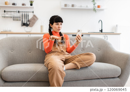 Young woman having video call on smartphone at home 120069045