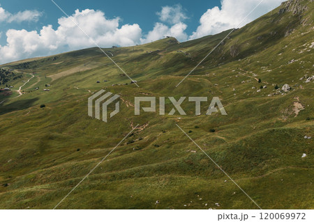 Experience the stunning and breathtaking landscape of the Dolomites featuring lush green hills and beautiful blue skies 120069972