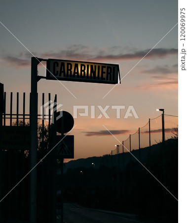 A Carabinieri sign of Italian military police force is clearly silhouetted against a beautifully colorful dusk sky during the evening. 120069975