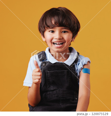 Asian child, portrait and thumbs up on studio background for vaccine, healthcare and illness prevention. Japanese boy, gesture or plaster on arm for flu shot, immune system strength or first aid help 120073129