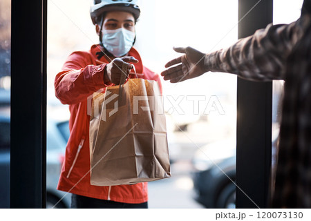 Weve got you covered during lockdown. Shot of a masked man delivering a food package. Weve got you covered during lockdown. Shot of a masked man delivering a food package. 120073130