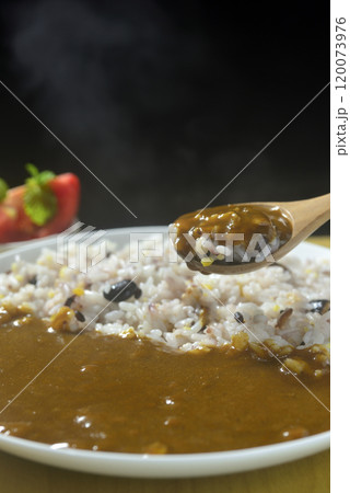 湯気の立つ雑穀とカレーをスプーンですくう 120073976