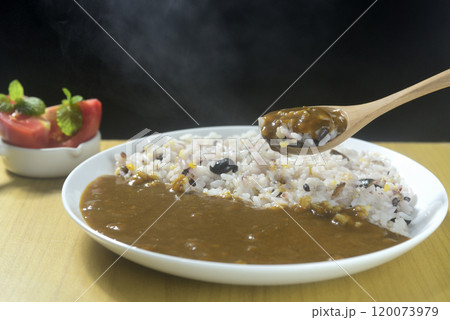 湯気の立つ雑穀とカレーをスプーンですくう 120073979