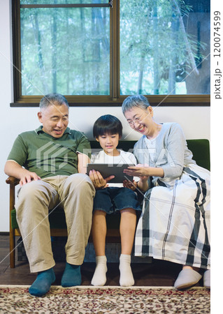 家でタブレットを一緒に楽しむ孫と祖父母 家でタブレットを一緒に楽しむ孫と祖父母 120074599