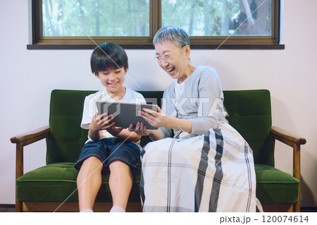 家でタブレットを一緒に楽しむ孫と祖母 家でタブレットを一緒に楽しむ孫と祖母 120074614