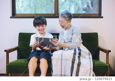 家でタブレットを一緒に楽しむ孫と祖母 家でタブレットを一緒に楽しむ孫と祖母 120074615