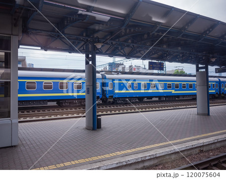 【ウクライナ】キーウ駅の閑散としたプラットホームと停車した青と黄色の鉄道車両 120075604
