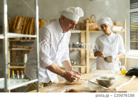 Man and woman, experienced bakers, prepare dough for baguettes and croissants together in private bakery 120076186