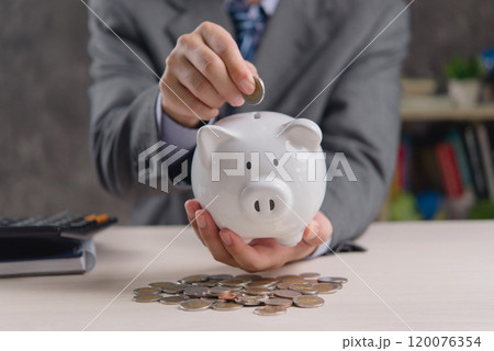 businessman holds a piggy bank as a concept of saving money for investment. Business related to taxes, money, finance, banking. businessman holds a piggy bank as a concept of saving money for investment. Business related to taxes, money, finance, banking. 120076354