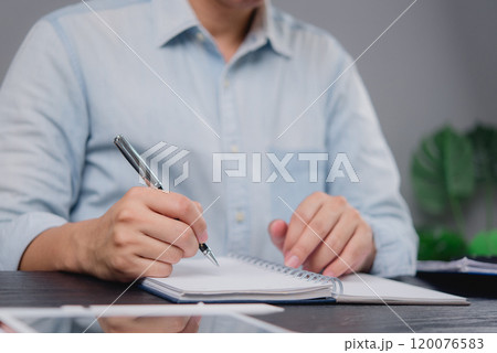 Business professional writing notes in a notebook. Ideal for themes around planning, strategy, or workplace organization in business environments. 120076583
