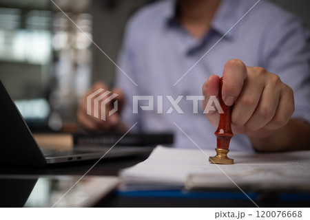 hand stamping a document in an office setting, symbolizing the process of approval and legal authentication in business and legal matters. Legal, business contract hand stamping a document in an office setting, symbolizing the process of approval and legal authentication in business and legal matters. Legal, business contract 120076668