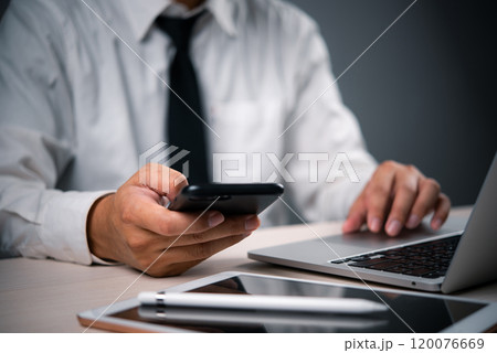 business professional multitasking using a smartphone and laptop, modern digital technology communication and multitasking in corporate environments. business professional multitasking using a smartphone and laptop, modern digital technology communication and multitasking in corporate environments. 120076669