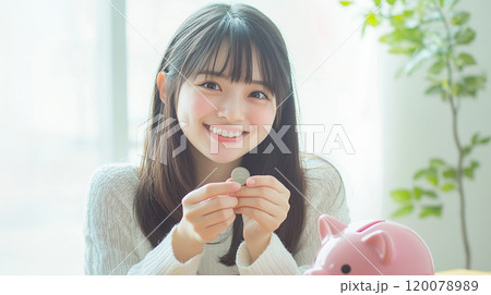 豚の貯金箱にコインを入れる笑顔の若い女性 120078989
