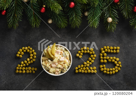 Figures 2025 of green peas with Russian salad on a dark stone background. 120080204