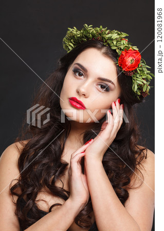 Cheerful healthy female model with shiny hair, make-up and spring flower on black background 120081968