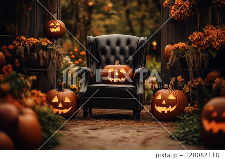A cozy autumn evening featuring a black chair surrounded by glowing jack-o'-lanterns and flowers 120082118