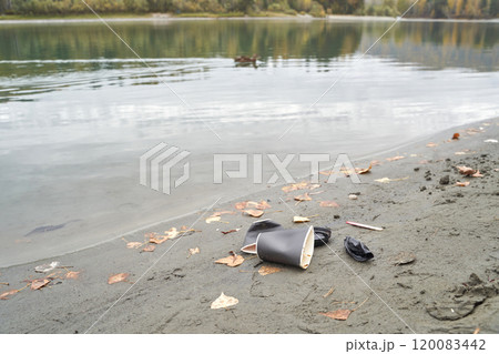 Pollution on riverbank with discarded cups and leaves illustrating environmental Pollution on riverbank with discarded cups and leaves illustrating environmental 120083442