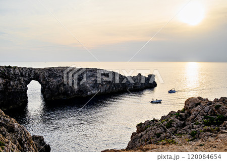 Spectacular sunset at Pont den Gil, Cala Corbetar in Ciutadella, Menorca, Balearic Islands. Peculiar natural formation in the form of an arch Spectacular sunset at Pont den Gil, Cala Corbetar in Ciutadella, Menorca, Balearic Islands. Peculiar natural formation in the form of an arch 120084654