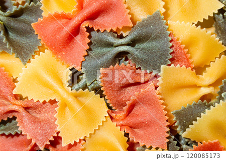 Dry Uncooked Colored Farfalle Pasta and Raw Macaroni on a Textured Background Dry Uncooked Colored Farfalle Pasta and Raw Macaroni on a Textured Background 120085173