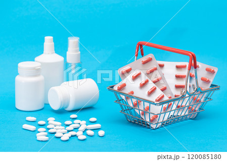 Pills and Capsules in Shopping Basket on Blue Background Pills and Capsules in Shopping Basket on Blue Background 120085180