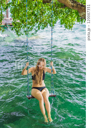 Beautiful female tourist relaxing on a swing in Laguna Bacalar in Mexico during kayak trip. Female tourist swinging over Lake Bacalar with feet in the water. Quintana Roo, Mexico travel, relaxation 120087351