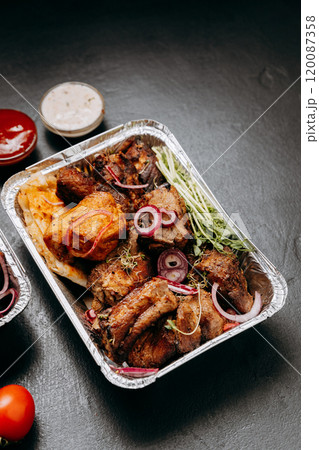 Delicious barbecue assortment in foil trays with tomatoes, sauces, ideal for catering and delivery 120087358