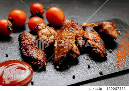 Juicy grilled chicken wings served with fresh tomatoes and spices, perfect for a delicious meal 120087381