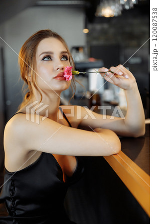 Elegant woman contemplating life while holding a flower at a stylish cafe 120087538