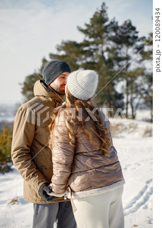 Portrait of romantic couple having fun on winter walk. Man and woman kissing. Family wearing warm jacket and knitted hats. Portrait of romantic couple having fun on winter walk. Man and woman kissing. Family wearing warm jacket and knitted hats. 120089434