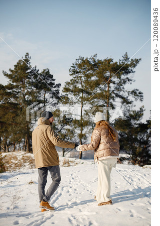 Portrait of romantic couple having fun on winter walk. Man and woman holding hands. Family wearing warm jacket and knitted hats. Portrait of romantic couple having fun on winter walk. Man and woman holding hands. Family wearing warm jacket and knitted hats. 120089436