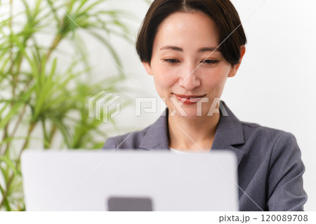 ビジネススーツを着てラップトップを操作している若い女性　ビジネスイメージ 120089708