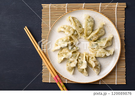 Steamed dumpling filled with pork and vegetables on dish and chopsticks Steamed dumpling filled with pork and vegetables on dish and chopsticks 120089876