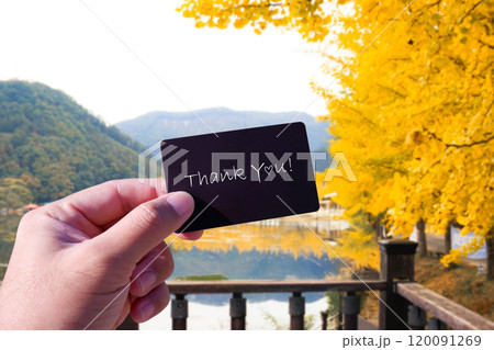 Thank You card in a hand against autumn landscape 120091269