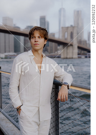A Stylish Young Man is Posing Confidently Near the Iconic Brooklyn Bridge in New York City 120092232