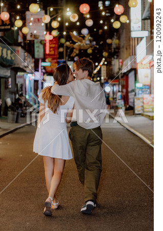 A couple strolls through a romantic urban night, enjoying a lively atmosphere and charm 120092243