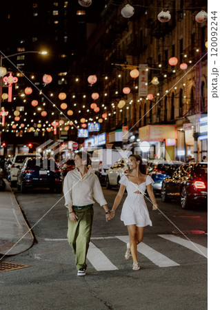 Charming couple strolling under festive city lights, fully embracing their special moment Charming couple strolling under festive city lights, fully embracing their special moment 120092244