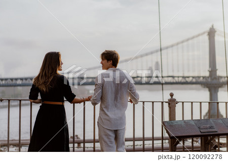 A Loving and Intimate Couple Embraces Tenderly with a Stunning Iconic Bridge in the Background A Loving and Intimate Couple Embraces Tenderly with a Stunning Iconic Bridge in the Background 120092278