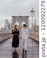 A couple is walking hand in hand across the Brooklyn Bridge as the sun rises beautifully 120092279