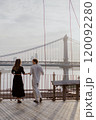 A Loving and Intimate Couple Embraces Tenderly with a Stunning Iconic Bridge in the Background 120092280